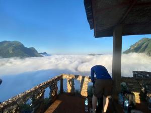 Ein Mann steht auf einem Balkon und schaut in die Wolken. in der Unterkunft Nong Khiaw Over Night Camping Sunrise and Sunset At Phadeng Peak Viewpoint in Ban Sôphoun