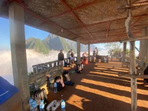 Eine Gruppe von Menschen sitzt auf einem Felsvorsprung mit Blick auf einen Berg. in der Unterkunft Nong Khiaw Over Night Camping Sunrise and Sunset At Phadeng Peak Viewpoint in Ban Sôphoun + 5 Fotos