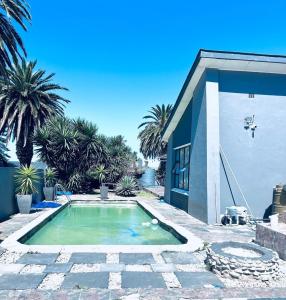 a swimming pool in front of a house with palm trees at Enez Place in Gqeberha