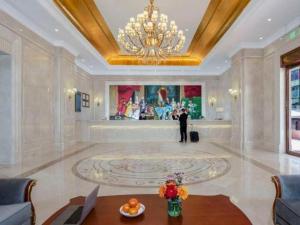a man standing in a large room with a chandelier at Vienna Hotel Shaanxi Hanzhong Central Square High-Speed Railway Station in Hanzhong