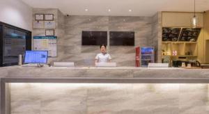 a woman standing behind a counter in a restaurant at City Comfort Inn Changning Wangchao in Changning