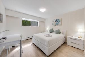 een witte slaapkamer met een bed en een bureau bij Vacation Home in Van West in Vancouver