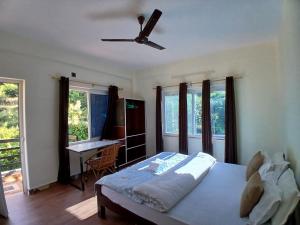 1 dormitorio con 1 cama, ventilador de techo y escritorio en JAP Guest House & Apartments, en Pokhara