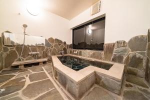 Un baño con bañera en una pared de roca. en 山小屋吉丁, en Ukiha