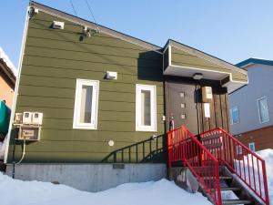 a green house with a red fence in the snow at Yume House in Kutchan
