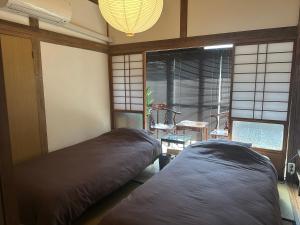 two beds in a room with a table and a window at GuestHouse" Ro "Umegato in Kogushi