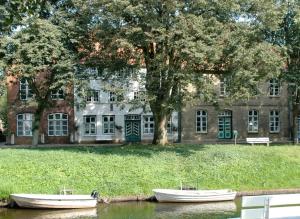two boats in the water in front of a building at Ferienwohnung Am Mittelburgwall in Friedrichstadt