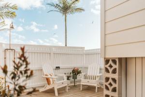 a porch with two chairs and a palm tree at George @ Ethel & Odes in Bundeena