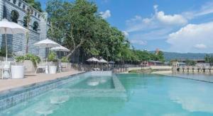 a swimming pool with blue water and umbrellas at Verona Boutique Hotel - The Verona Co., Ltd in Ban Wang Khon Daeng