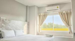 ein weißes Schlafzimmer mit einem Bett und einem Fenster in der Unterkunft Kosit One Hotel in Ban Bung Sam Phan Nok