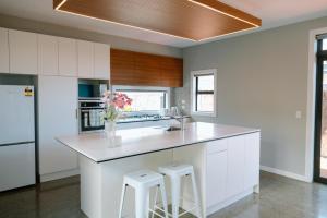 a kitchen with white cabinets and a counter with stools at Sunny and Modern Nelson Retreat with Designer Kitchen in Nelson