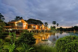 a row of houses next to a river at night at Nornnadubua in Ban Nam Tok