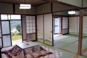 Zimmer mit einem Tisch in einem Zimmer mit Fenstern in der Unterkunft 星空と田園風景のウェルカムハウス in Uwano