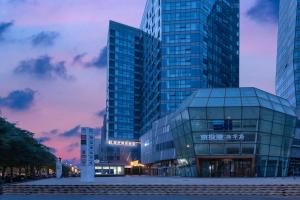 un grand bâtiment en verre dans une ville au crépuscule dans l'établissement Kouring Ruiyue Hotel Guogongzhuang Subway Station Branch, à Pékin