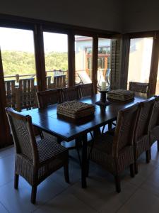 a dining room table and chairs with a view of a balcony at Plettenberg Bay Getaway in Plettenberg Bay