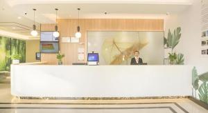 HudaiにあるGreenTree Inn Express Taizhou Jiangyan Hardware Cityの職場の窓口に座る男