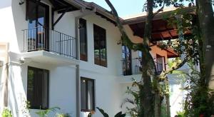 a white house with balconies and a tree at The MGS Hotel in Kadirandola