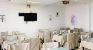 Un comedor con mesas y sillas y un televisor. en GreenTree Inn Heze Mudan Road Bus Terminal Station Express Hotel, en Heze