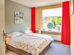 a bedroom with a bed and a window with red curtains at Stunning apartment in Schoorl, North Hollandâ you can bike to the beach in Schoorl