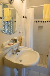 a white bathroom with a sink and a shower at Dunlop Inn in Baddeck