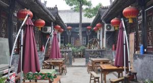 Un restaurante con sombrillas rojas, mesas y sillas. en Pingyao Yufengheng Hotel, en Pingyao