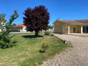 a house with a tree in front of a yard at Chambre avec un lit King size in Le Pizou