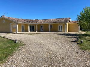 a large yellow house with a gravel driveway at Chambre avec un lit King size in Le Pizou