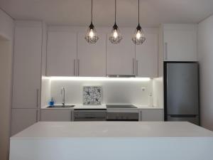 una cucina con armadietti bianchi, frigorifero e luci di Lagoa Princess Condo a Lagoa