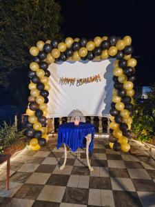 a person sitting at a table in front of a arch of balloons at MAHABALESHWAR HERITAGE villa in Kelghar