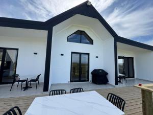 a white house with a table and chairs on a deck at Plettenvale Wines in Plettenberg Bay