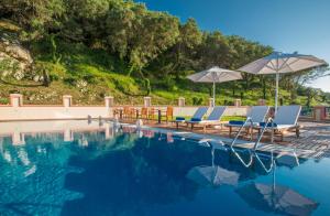 a swimming pool with chairs and umbrellas at Philoxenia in Ermones