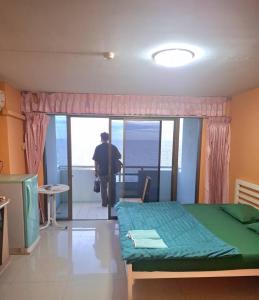 a man standing in a room with a bed at Bangsaen Royal Beach Seaview Room in Ban Laem Thaen