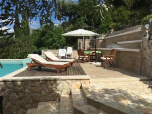 un patio con sillas y una sombrilla junto a la piscina en Villa Miolin, en Trpanj