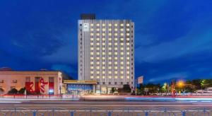 上海市にあるYitel Premium Hotel Shanghai Xuhuiの建物の前にライトが付いた背の高い白い建物