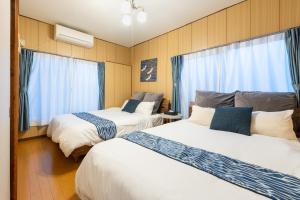 two beds in a room with blue curtains at ぱんだホステル三ノ輪 Panda Hostel Minowa in Wada