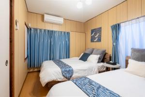 two beds in a room with blue curtains at ぱんだホステル三ノ輪 Panda Hostel Minowa in Wada +15 photos