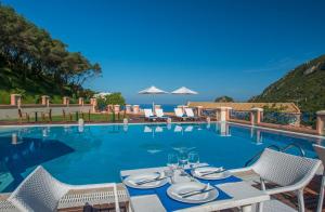 a swimming pool with a table and chairs in front of it at Philoxenia in Ermones