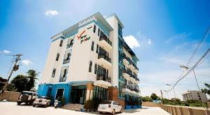 Un edificio blanco con coches aparcados delante. en The Viewpoint Hotel, en Ban Wat Tha Maprang