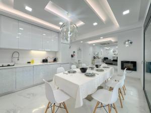 ein weißes Esszimmer mit einem weißen Tisch und weißen Stühlen in der Unterkunft Diamond Luxury Villa Corfu in Káto Spílaion