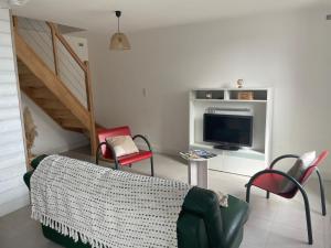 ein Wohnzimmer mit einem Sofa, Stühlen und einem TV in der Unterkunft Maison en campagne in Mortagne-sur-Sèvre