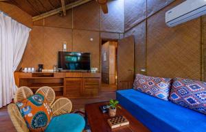 a living room with a blue couch and a television at ONENESS Rishikesh by Ganga Kinare - A Luxury Wilderness Resort in Rishīkesh