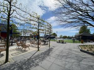 a patio with tables and chairs and trees at Moderne chalet met hottub in Lathum