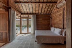 a bedroom with a bed and a wooden wall at Kalyana Villa Gili Air in Gili Air