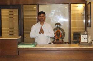 Ein Mann steht mit gefalteten Händen vor einem Tresen. in der Unterkunft Khanna Residency in Neu-Delhi