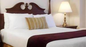 een slaapkamer met een groot bed met witte lakens en een lamp bij Hilgard House Westwood Village in Los Angeles