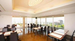 a dining room with tables and chairs and windows at Green Hotel Yes Nagahama Minatokan in Nagahama
