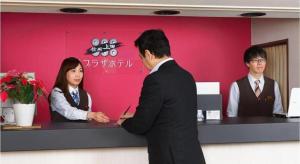 a man in a suit standing in front of a counter at Ueda Plaza Hotel in Ueda