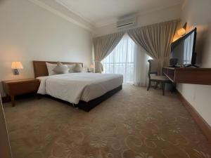 a hotel room with a bed and a flat screen tv at Putra Brasmana Hotel in Kuala Perlis +123 photos