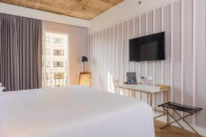 a bedroom with a bed and a tv on the wall at Faranda Collection Barranquilla, a member of Radisson Individuals in Barranquilla