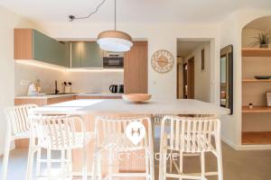 a kitchen with a table and some white chairs at SELECT'soHOME - Jardin vue mer à Pramousquier - ASTRA in Rayol-Canadel-sur-Mer